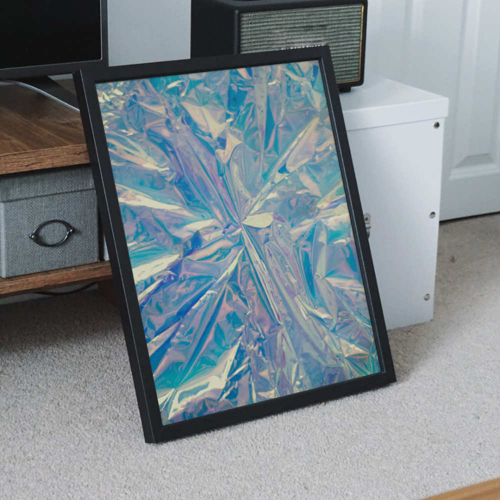 Framed Blue Botanical Burst abstract wall art print leaning against a white wall in a modern room, showcasing its vibrant blue, teal, and beige floral design in a close-up home setting.