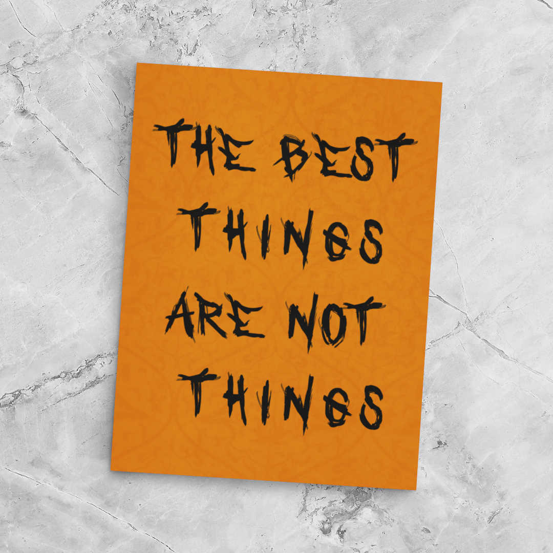 Orange poster with black text 'The best things are not things' on a gray marble background